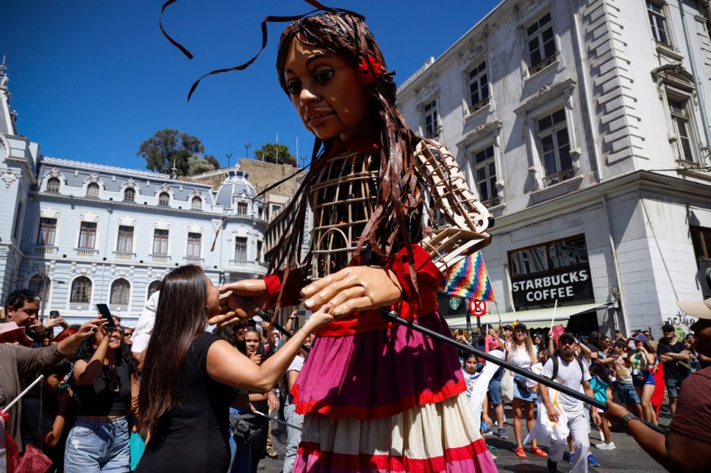 Amal, la marioneta gigante, caminando por las calles de Valparaíso, rodeada de niños emocionados