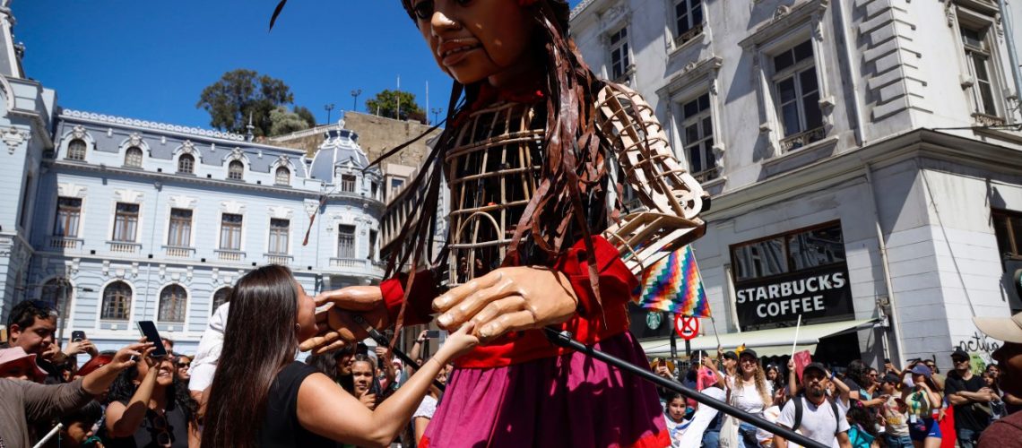 Amal, la marioneta gigante, caminando por las calles de Valparaíso, rodeada de niños emocionados